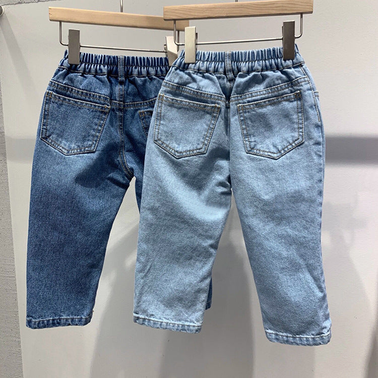 Two pairs of cotton denim jeans hang on hangers, one in dark blue and one in light blue, showing elastic waists and pockets.