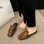 Brown and black leopard print pointed-toe mules with black trim, worn with black trousers.