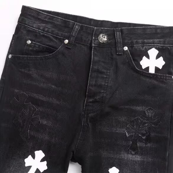 Black denim jeans with white and dark cross patches, silver rivets, and a decorative button closure.