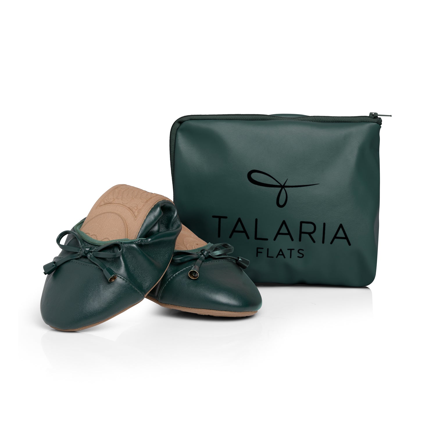 Green Talaria Flats footwear with premium evergreen color, folded in front of a bag, showcasing stylish and comfortable shoes.