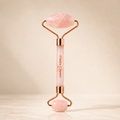 Rose quartz facial roller device by Timeless Organics Skin Care, showing a pink stone roller used for facial massage and skincare.