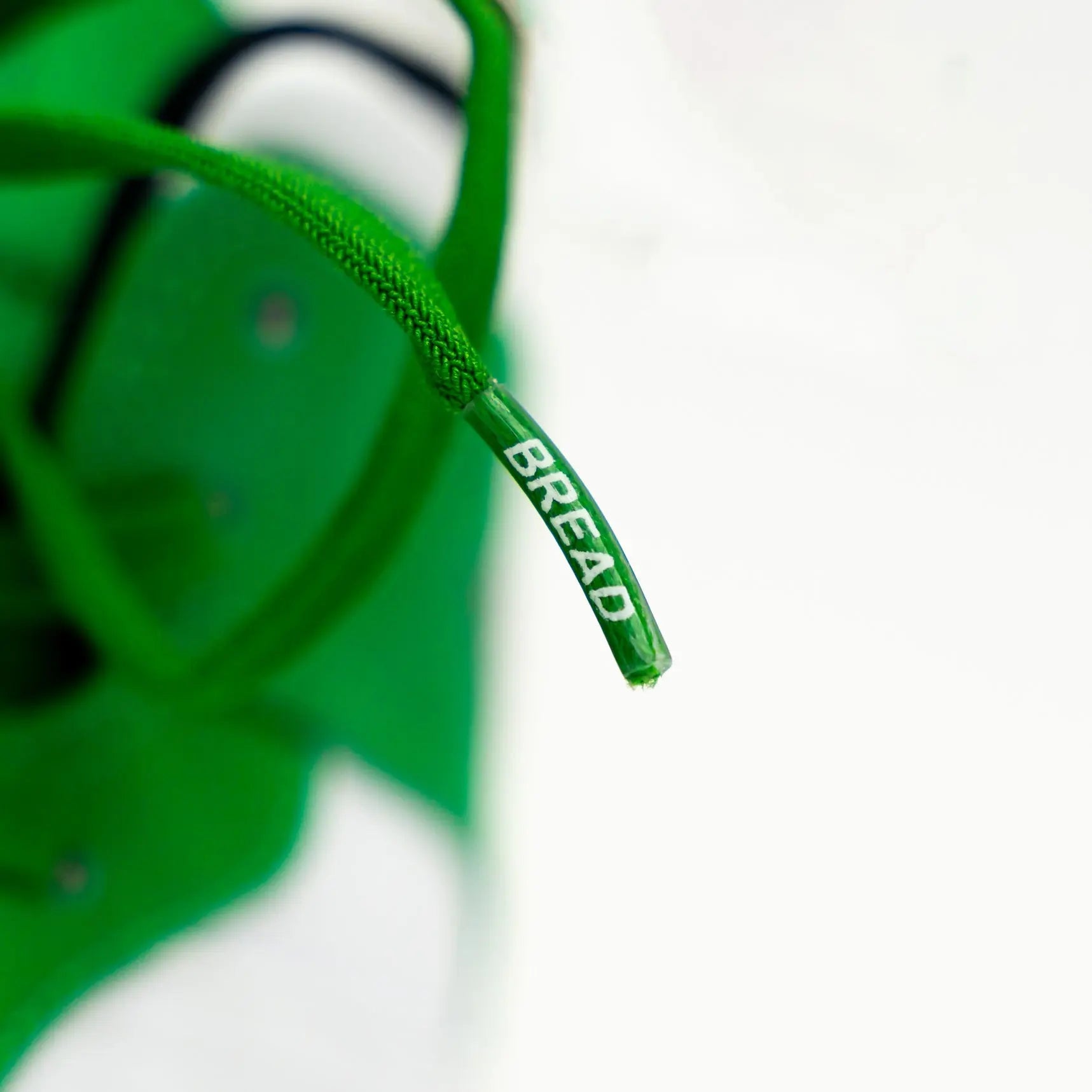 Elastic shoelace in Lucky Green by Bread, shown threaded through sneakers with a vibrant green color and flexible design.