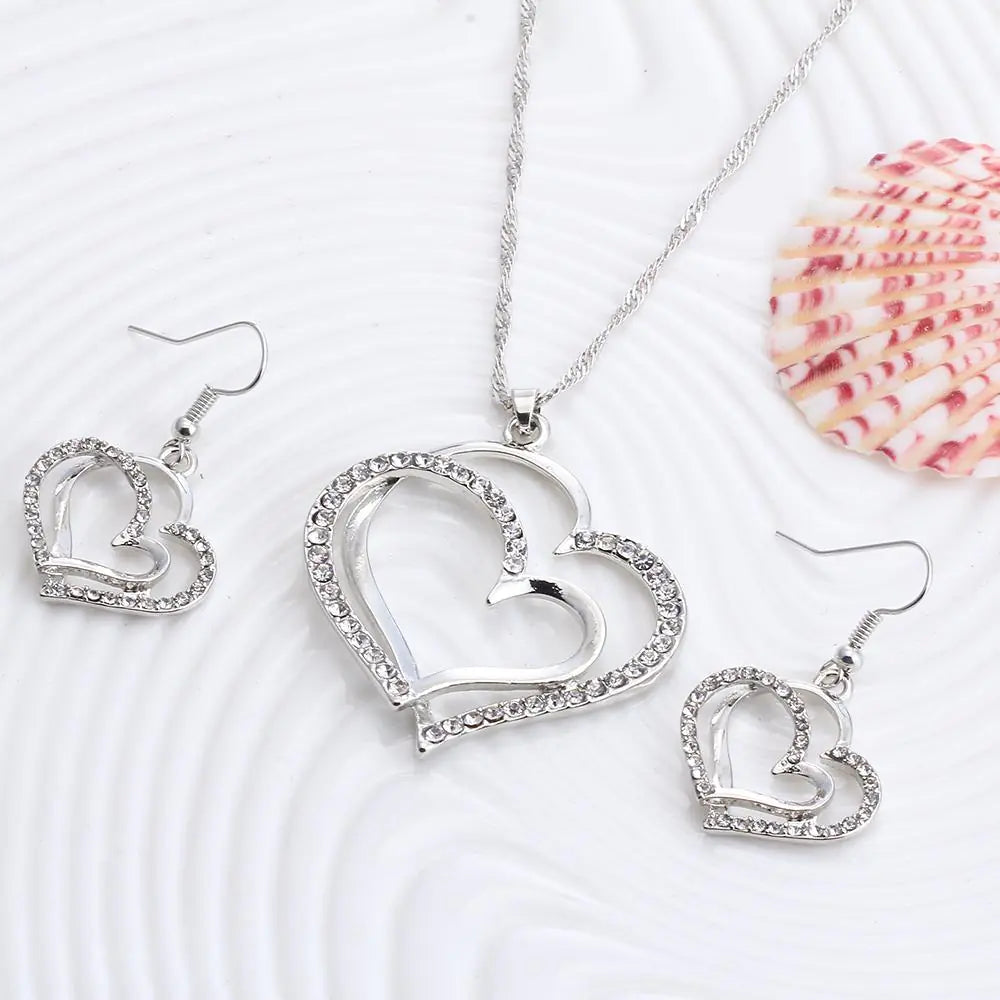 Double heart earrings and necklace wedding set featuring silver-tone jewelry with elegant heart-shaped designs.