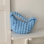 Handmade crocheted beige straw beach bag with solid color, hand-carry style, perfect for seaside or vacation use by women.