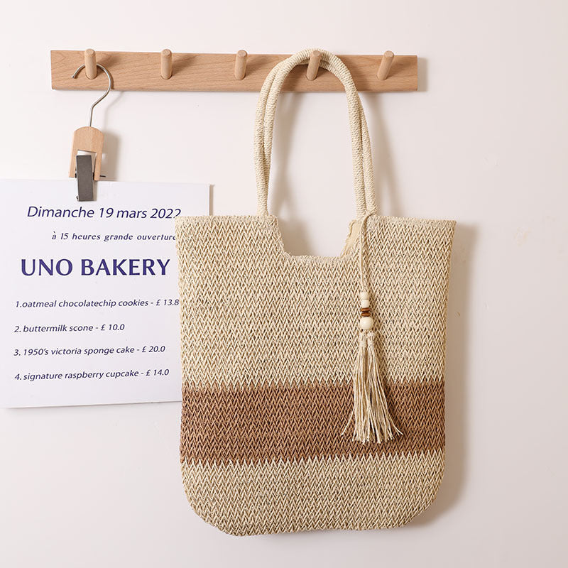 Woven two-tone tassel shoulder bag with straw design, casual beach bag for women, featuring woven texture and tassel accents.
