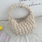 Handmade beige crocheted straw beach bag with handles, portable and solid-colored, ideal for seaside vacations and casual outings.