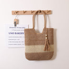 Woven two-tone tassel shoulder bag by Wanita Store, casual straw beach bag with tassel accents for women.