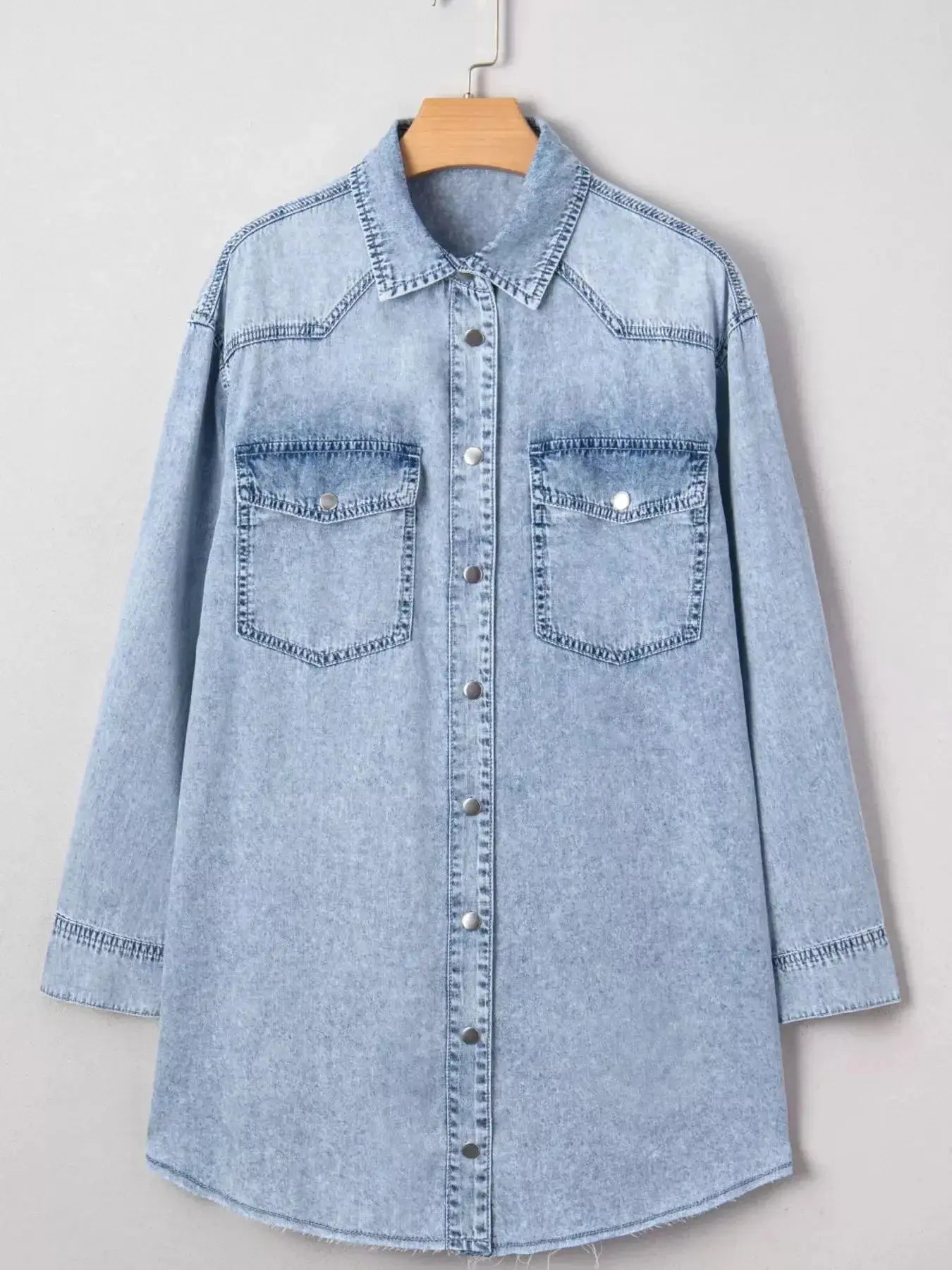 Raw hem denim button-down shirt dress with pockets, relaxed cotton fit, by Trendsi, shown on a hanger with rolled-up sleeves.