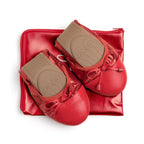 Talaria Flats premium ruby red flats shoes resting on a bag, showcasing their stylish design and vibrant color.