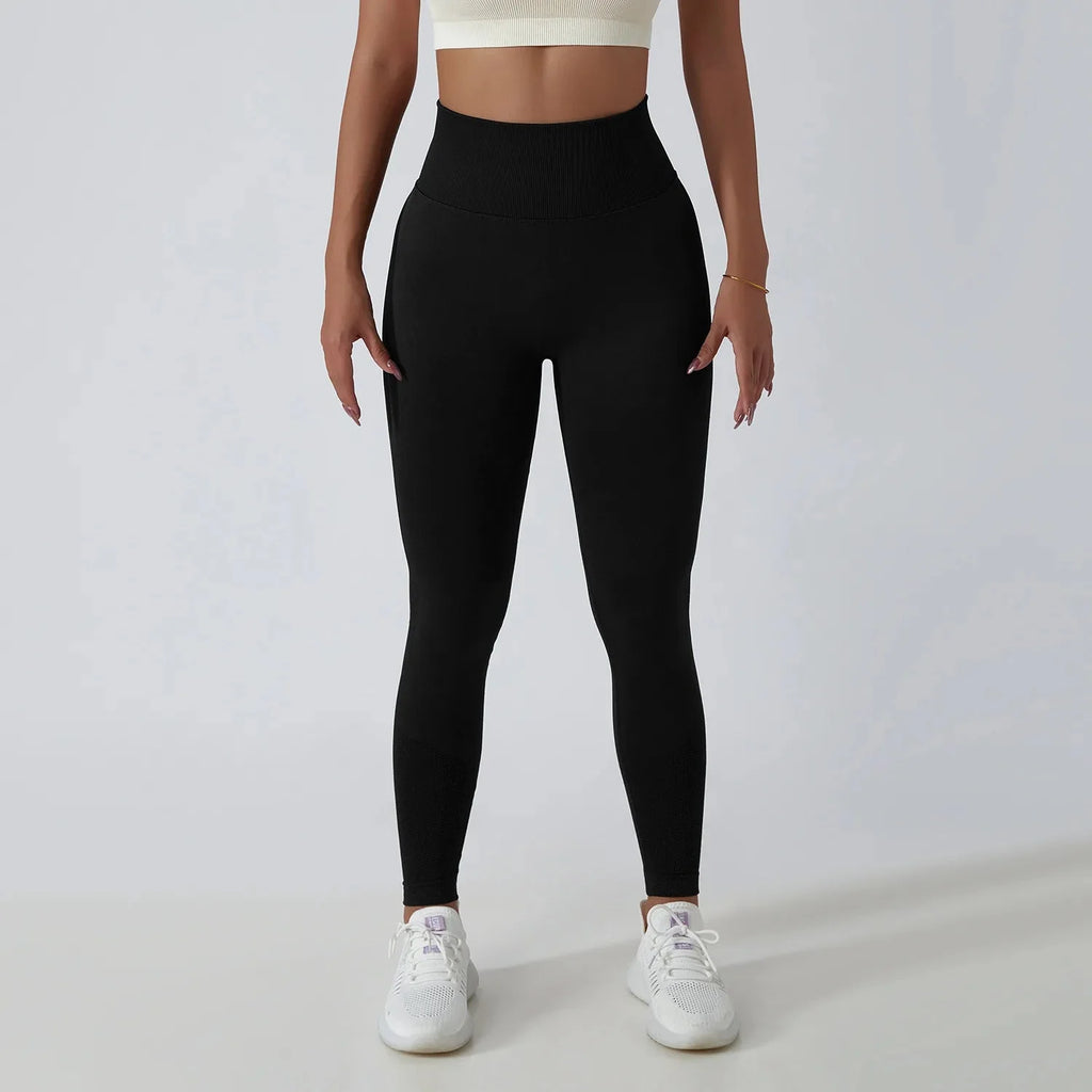 Black seamless ribbed yoga leggings with tummy control fit from FitiqueFit, designed for activewear and comfortable movement.