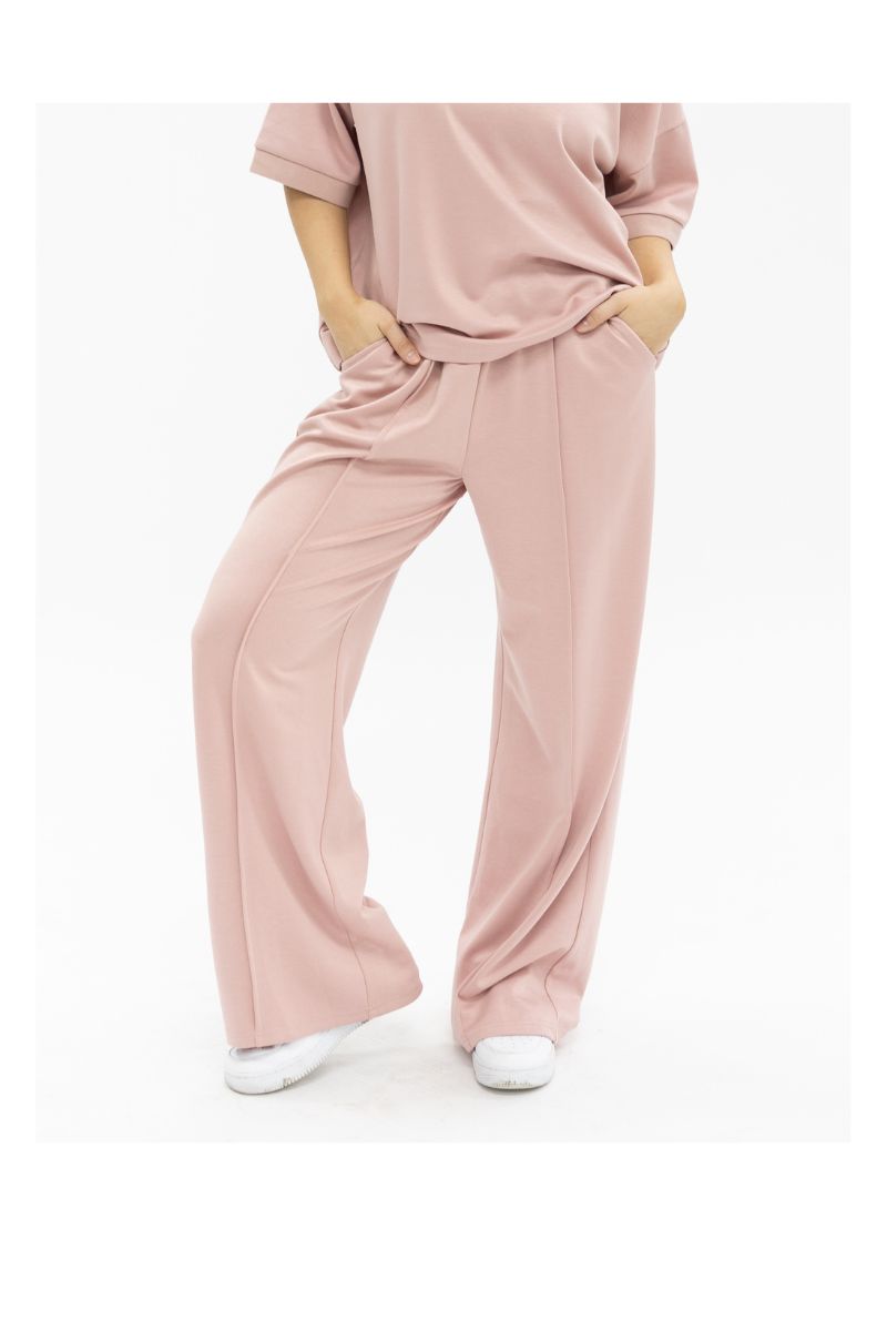 A model wears pink wide-leg ladies pants with center seams and front pockets, paired with a matching t-shirt.