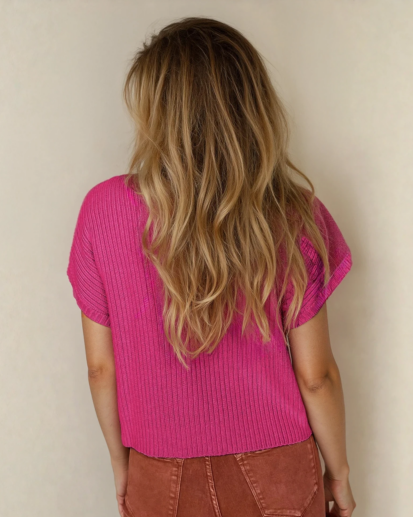 Bright pink Ayla short sleeve sweater by Indie & Co., styled as a knit top, displayed on a wooden floor background.