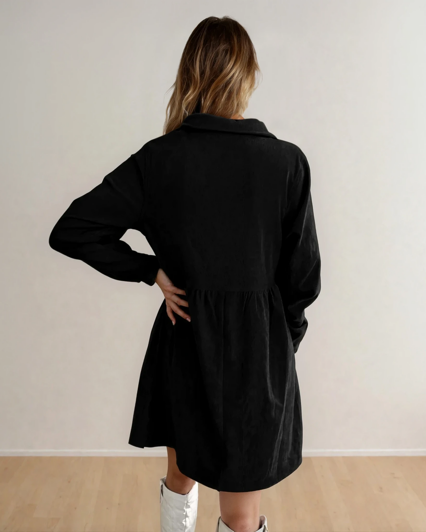 Black Abigail corduroy dress by Indie & Co. featuring a half-button front, collar, and long sleeves, displayed on a hardwood floor background.