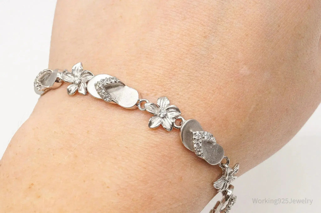 Sterling silver bracelet with floral and cubic zirconia accents, paired with vintage sandals featuring cubic zirconia details.