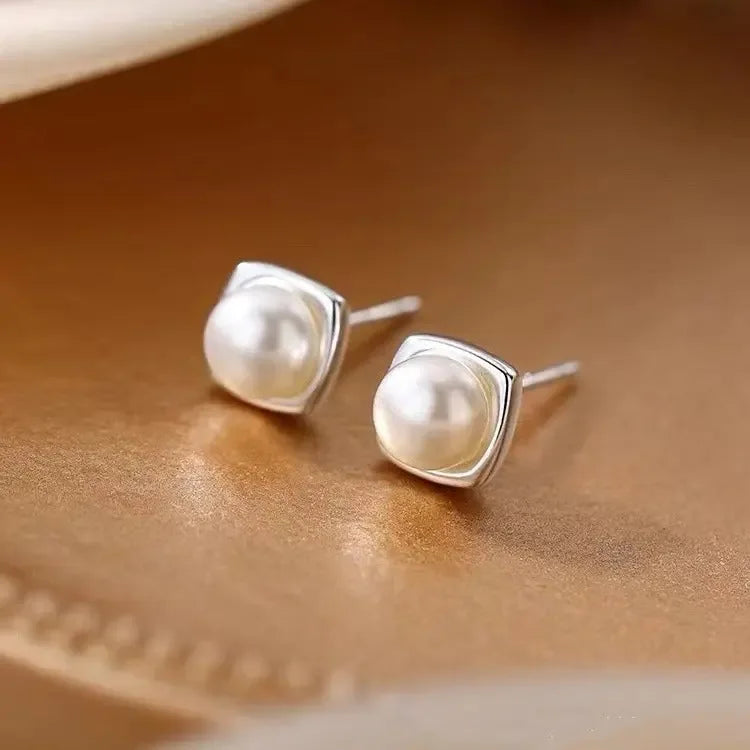 Elegant minimalist 925 sterling silver pearl stud earrings featuring geometric design, perfect for sophisticated women.