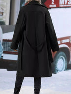 Women’s double-breasted trench coat by Trendsi with tie waist belt, shown in a stylish outdoor setting.
