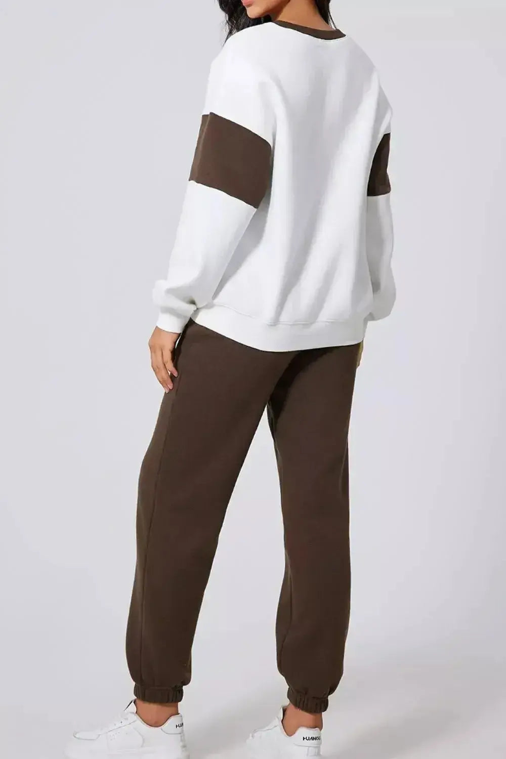 Women wearing a trendy oversized drop shoulder sweatshirt and matching joggers loungewear set by Trendsi, casual and comfortable fit.