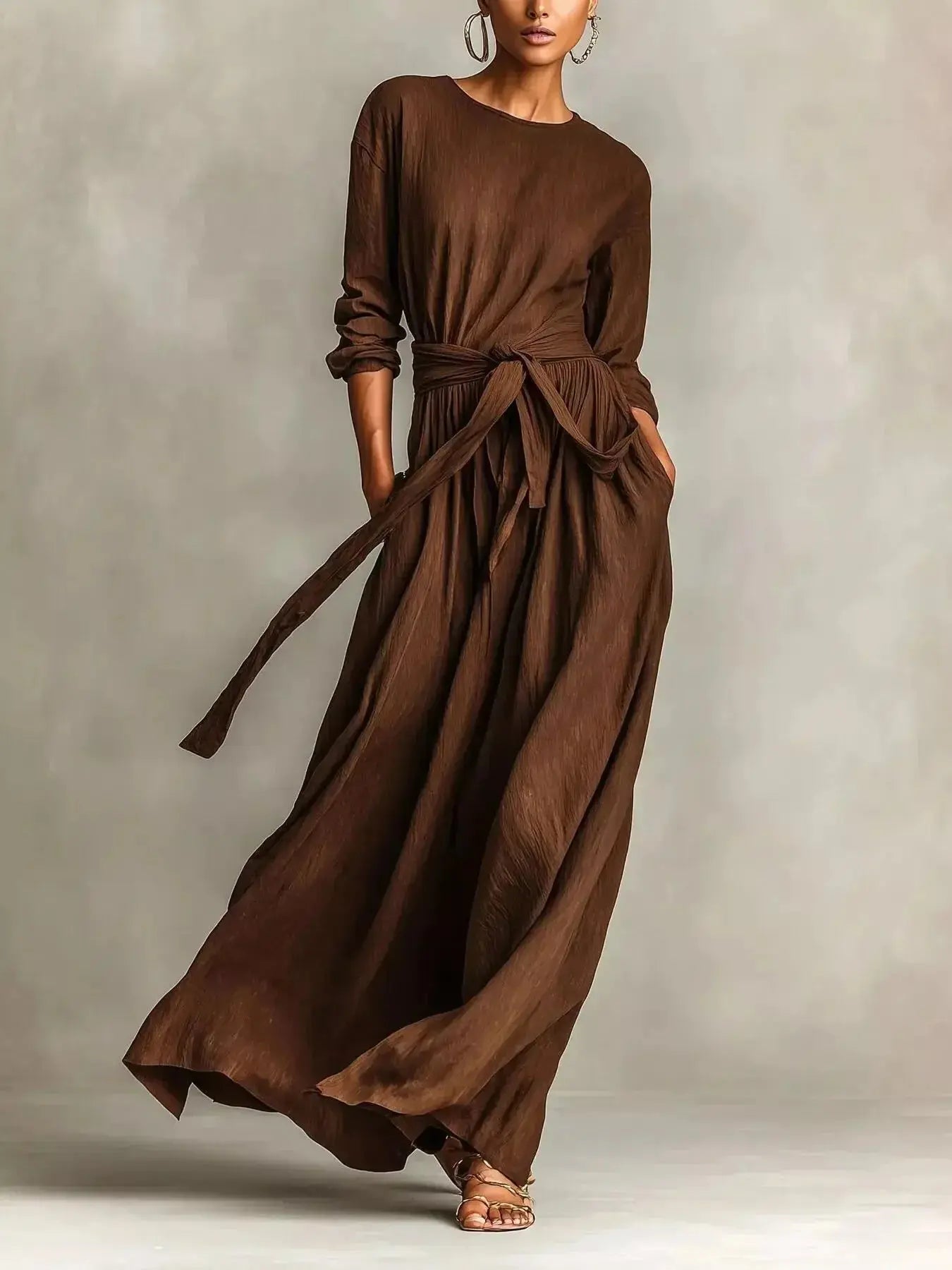 Plus size women's long sleeve maxi dress with tie waist and pockets, by Trendsi, shown on a model with a flowing fabric design.