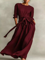 Plus size women's long sleeve maxi dress with tie waist and pockets by Trendsi, shown in a flowing, stylish design.