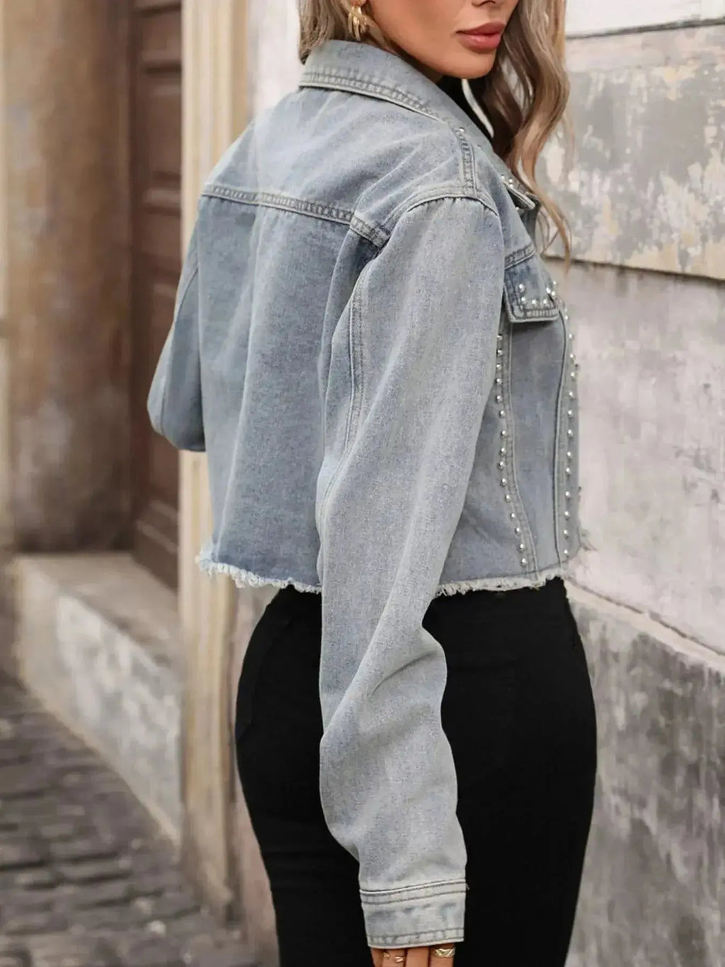 Women’s studded raw hem denim jacket by Trendsi, featuring distressed style, metal stud embellishments, and casual distressed denim look.
