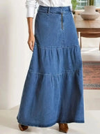 Women's tiered maxi denim skirt with ruched zipper detail from Trendsi, featuring a flowy design and stylish accents.