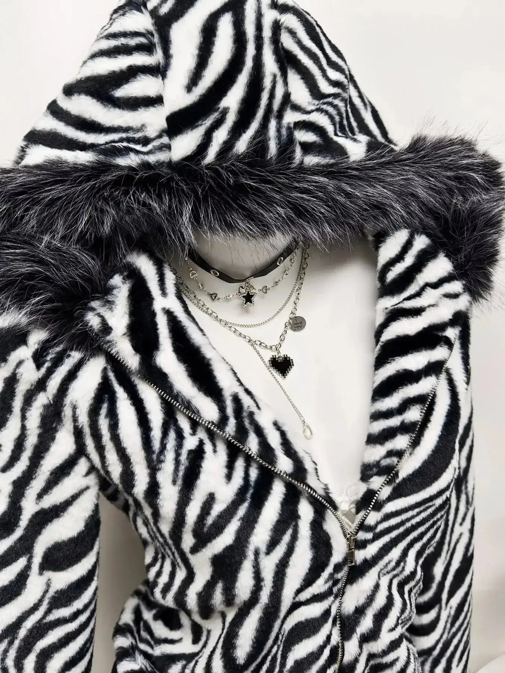 Zebra faux fur hooded zip-up jacket from Trendsi, plush and stylish with a furry zebra print, front zipper, and hood.