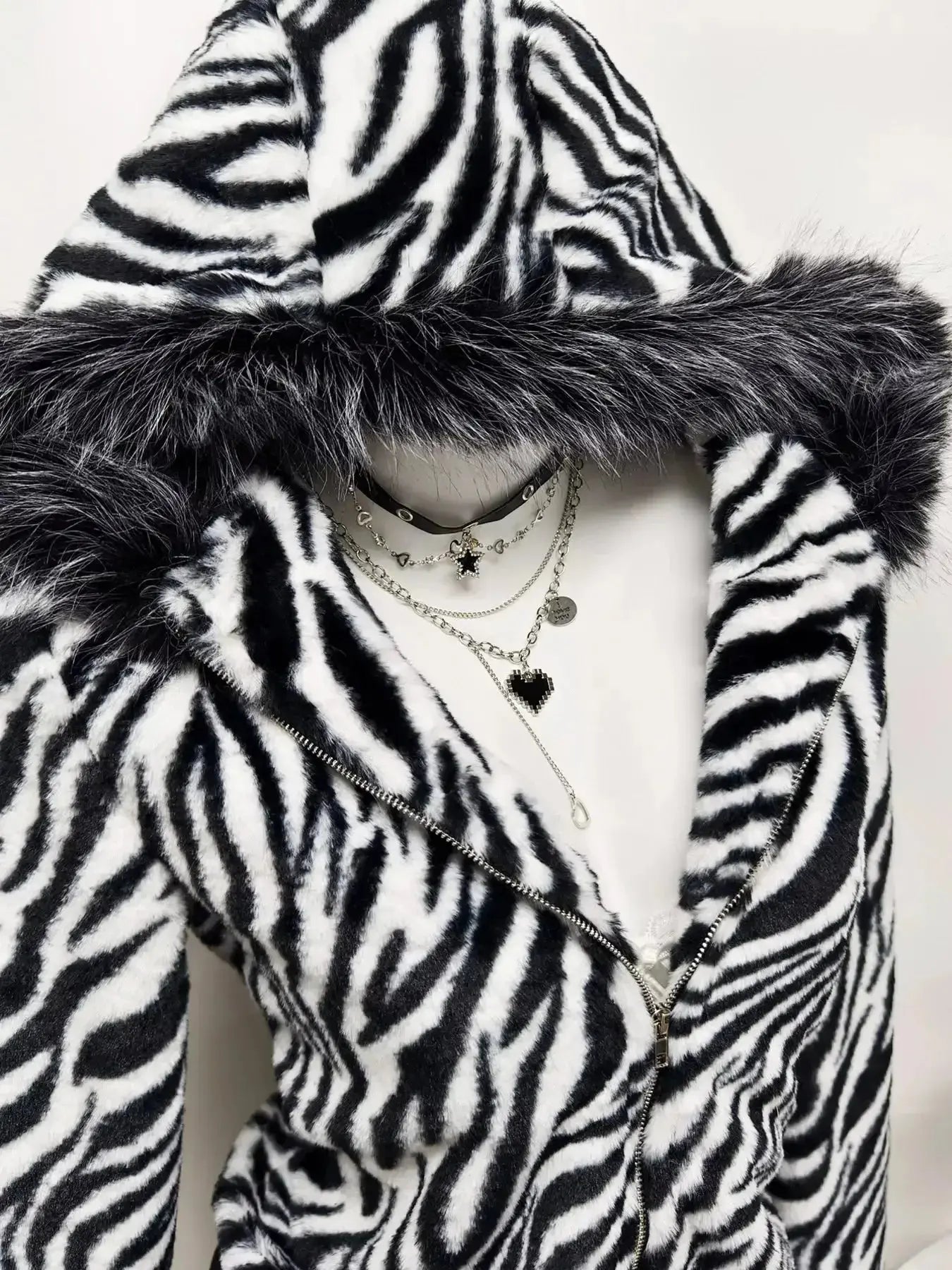 Zebra faux fur hooded zip-up jacket from Trendsi, plush and stylish with a furry zebra print, front zipper, and hood.