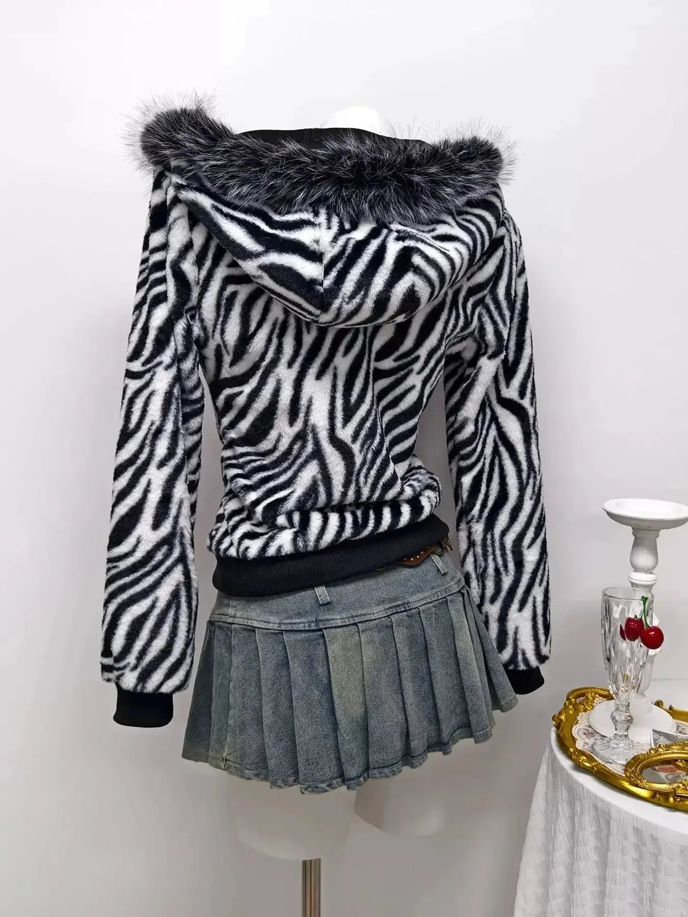 Zebra faux fur hooded zip-up jacket from Trendsi, showing plush black and white zebra print with front zipper and hood.
