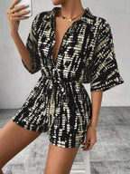 Striped button-up belted romper jumpsuit by Trendsi, featuring a stylish design with a waist belt and long sleeves.