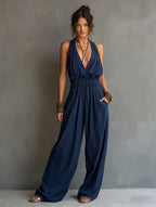 Women's sleeveless V-neck halter jumpsuit with open back and cinched waist, by Plush Fashion Hub, shown on a model.