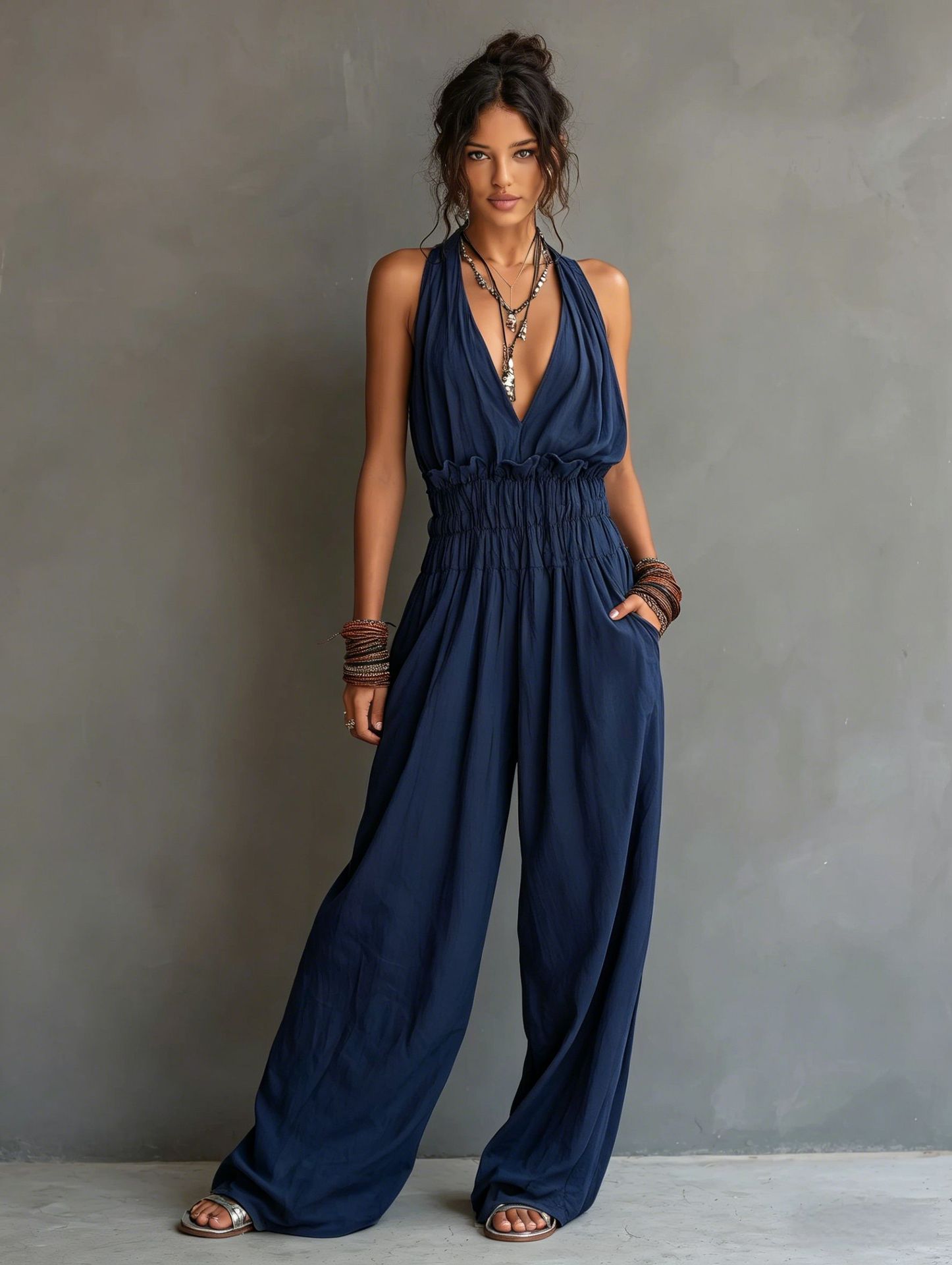 Women's sleeveless V-neck halter jumpsuit with open back and cinched waist, by Plush Fashion Hub, shown on a model.