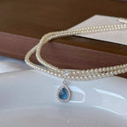 Double layered pearl necklace by Shopimist with teardrop pendant, featuring lustrous pearls and elegant gold accents.