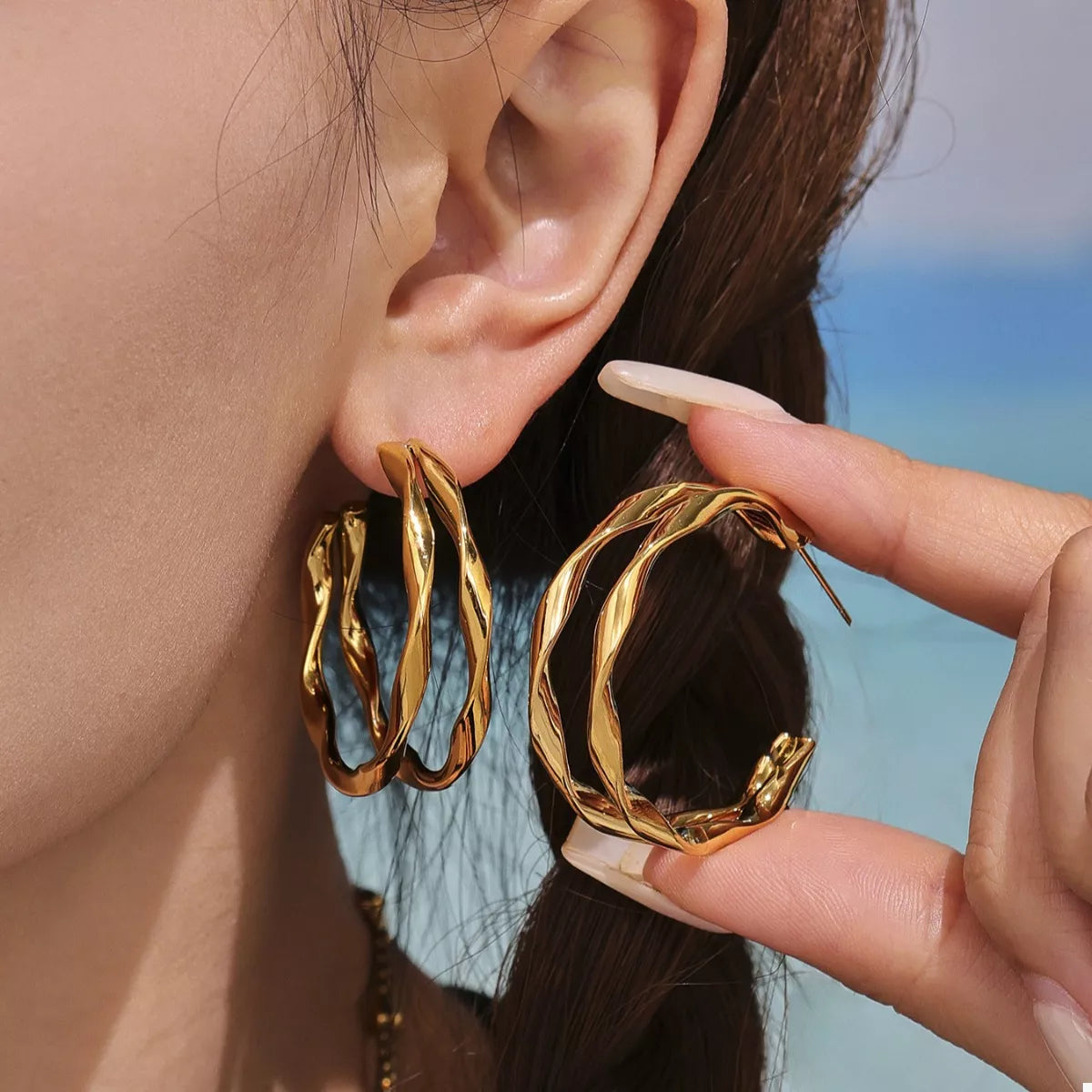 Gold-plated chunky twisted hoop earrings with a bold, stylish design, perfect for adding a statement touch to any outfit.
