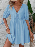 Cotton V-neck tie-front mini dress with puff sleeves, trendy fashion by Trendsi, perfect for casual or summer wear.