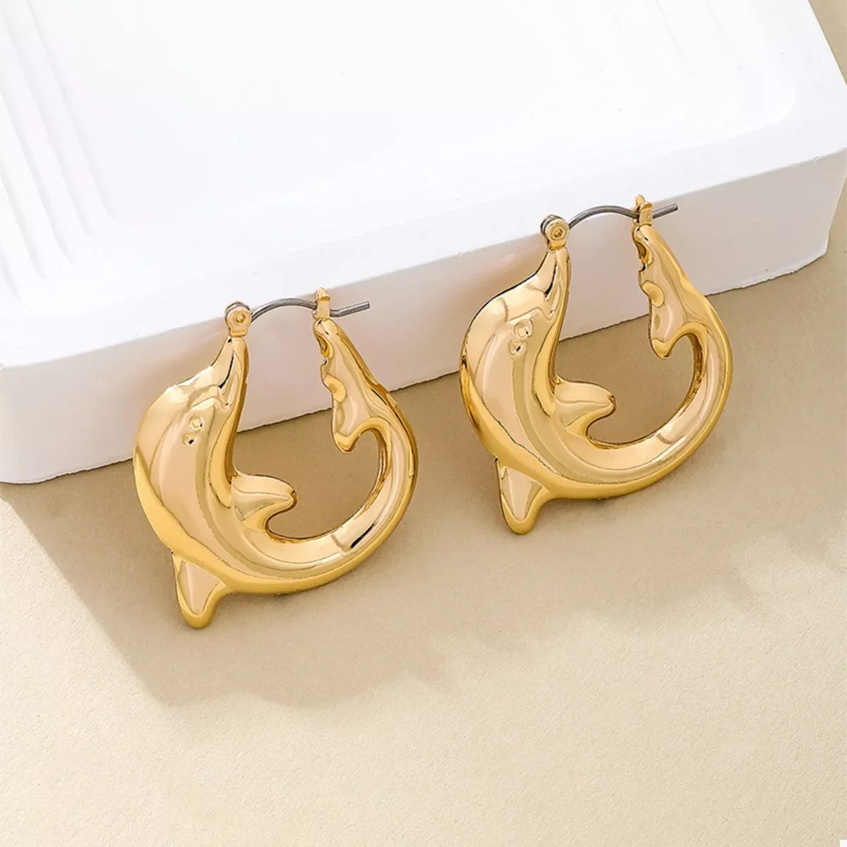 Gold-plated dolphin hoop earrings from Plush Fashion Hub featuring sleek, shiny jewelry with a playful dolphin design.