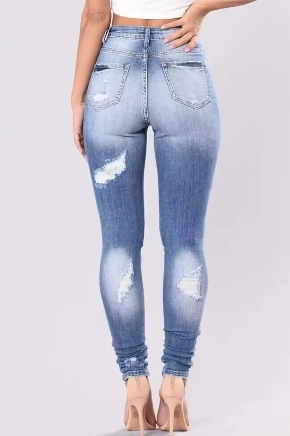 Plus size full distressed skinny denim jeans by Trendsi, featuring a fitted silhouette and ripped details on dark blue denim.