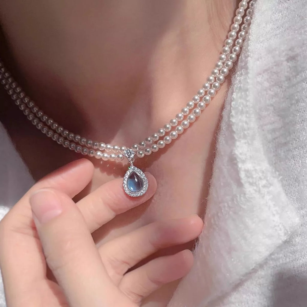 Double layered pearl necklace from Shopimist with a teardrop pendant, featuring elegant pearls on a delicate chain.