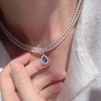 Double layered pearl necklace from Shopimist with a teardrop pendant, featuring elegant pearls on a delicate chain.