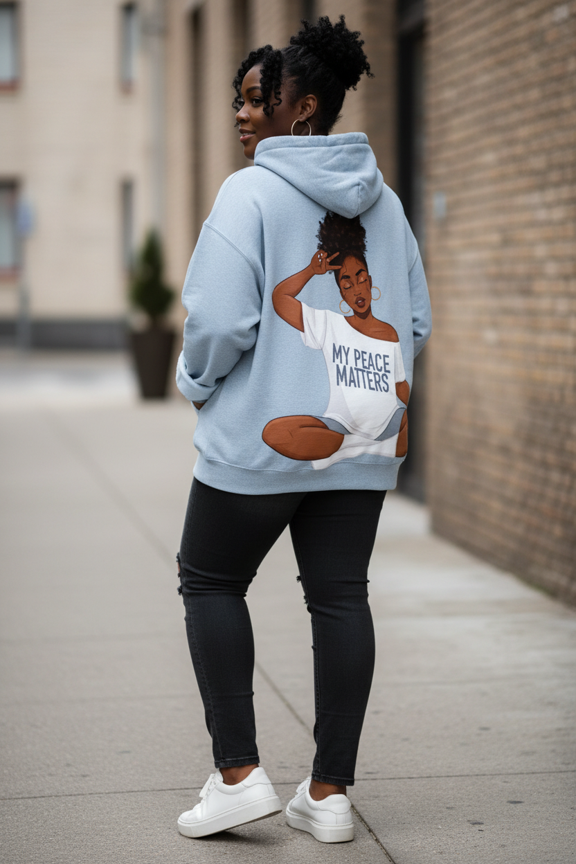 Back of a light blue fleece hoodie with a Black woman graphic reading "My Peace Matters" worn with black jeans.