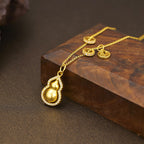 18K gold-plated gourd pendant necklace with intricate design, hanging on a delicate chain, displayed against a neutral background.