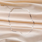 Sterling silver chain necklace with a delicate design, featuring 925 silver, displayed on a neutral background.