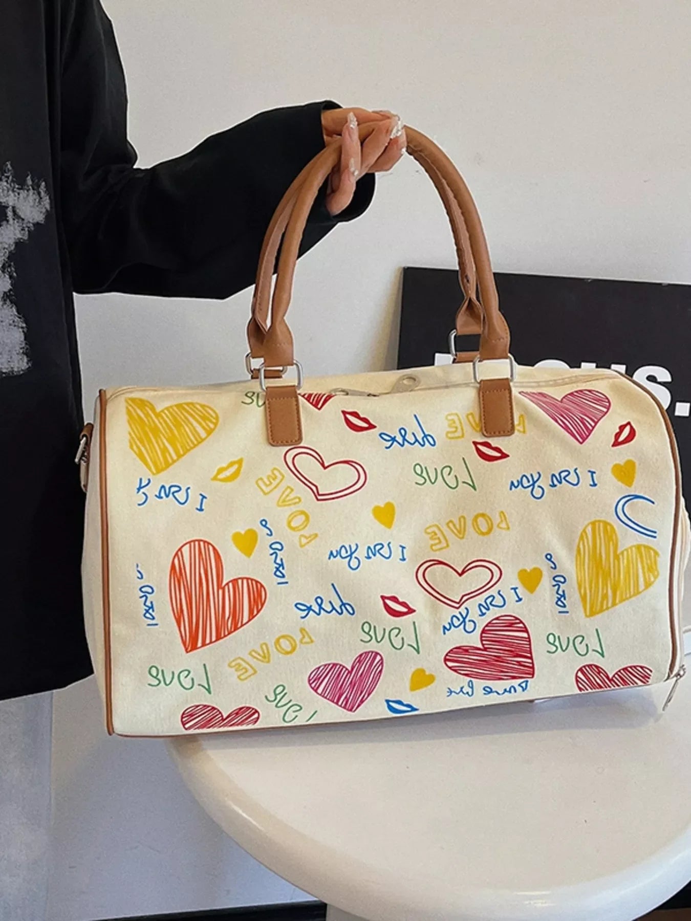 Printed duffel bag with adjustable strap from Plush Fashion Hub, showing a spacious bag with colorful printed design and sturdy handle.