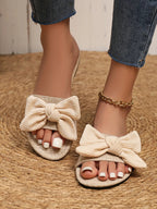Women's open toe flat sandals with bow accent by Trendsi, featuring comfortable slip-on design for summer wear.