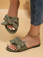 Women's open-toe flat sandals with bow accents from Trendsi, featuring comfortable slip-on design for summer wear.