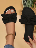 Women's open toe flat sandals with bow accent from Trendsi, featuring a chic design and slip-on style for summer comfort.