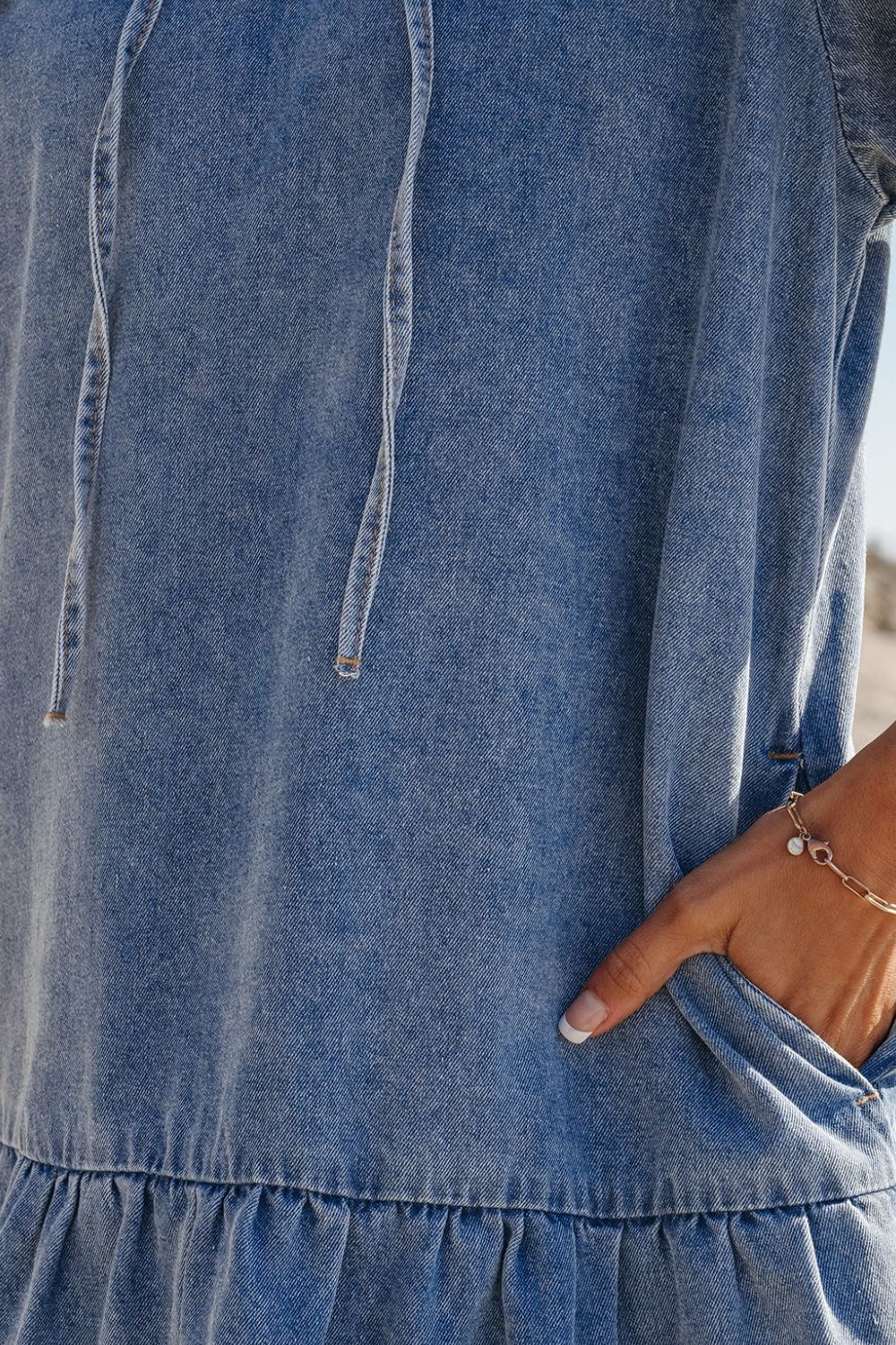 VYSN denim mini dress with ruffled side pockets and puff sleeves, casual fashion clothing displayed on a hanger.