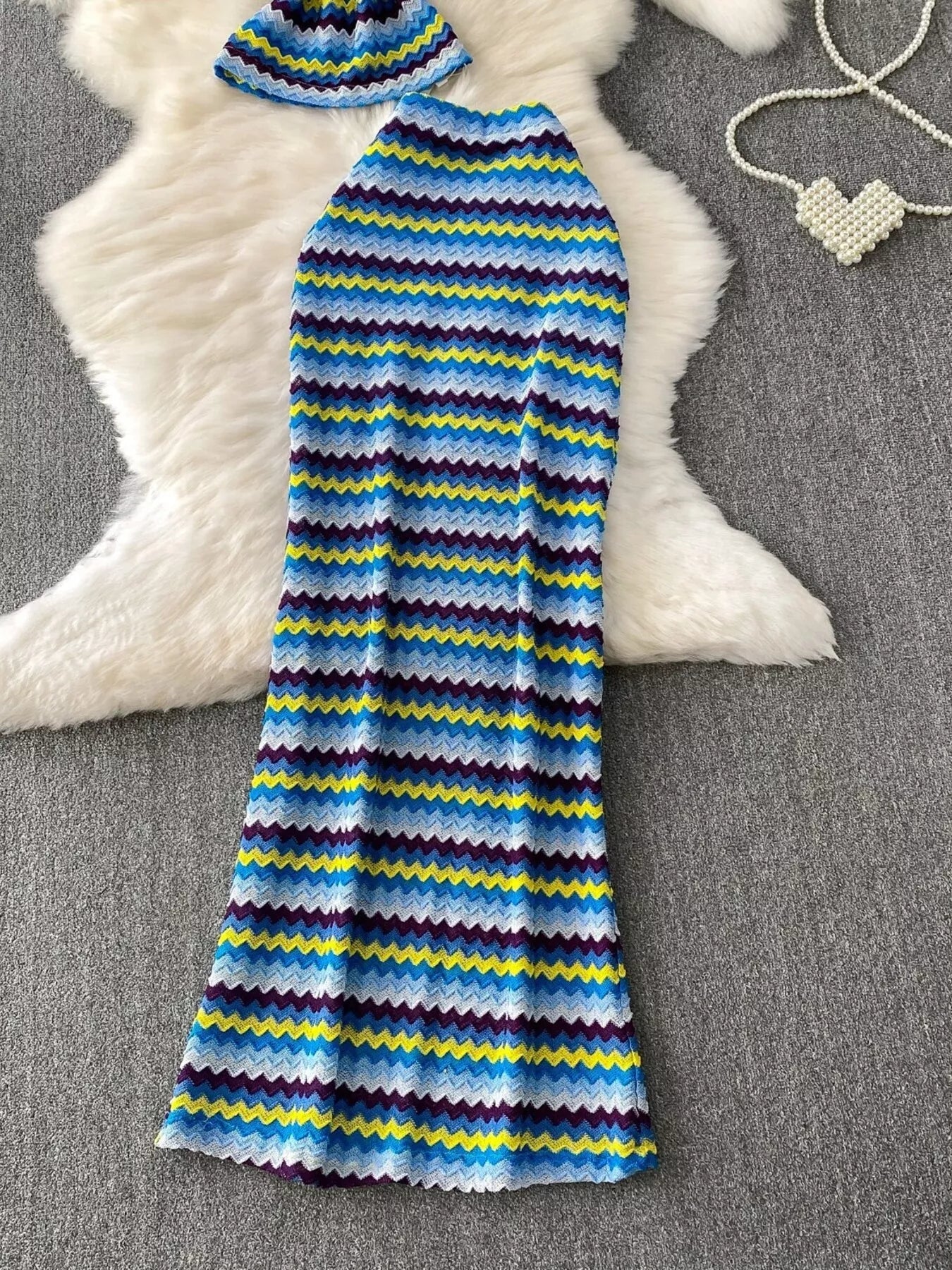 Women's striped knitted halter top and maxi skirt dress set by Trendsi, featuring a stylish, comfortable knit fabric and vibrant pattern.