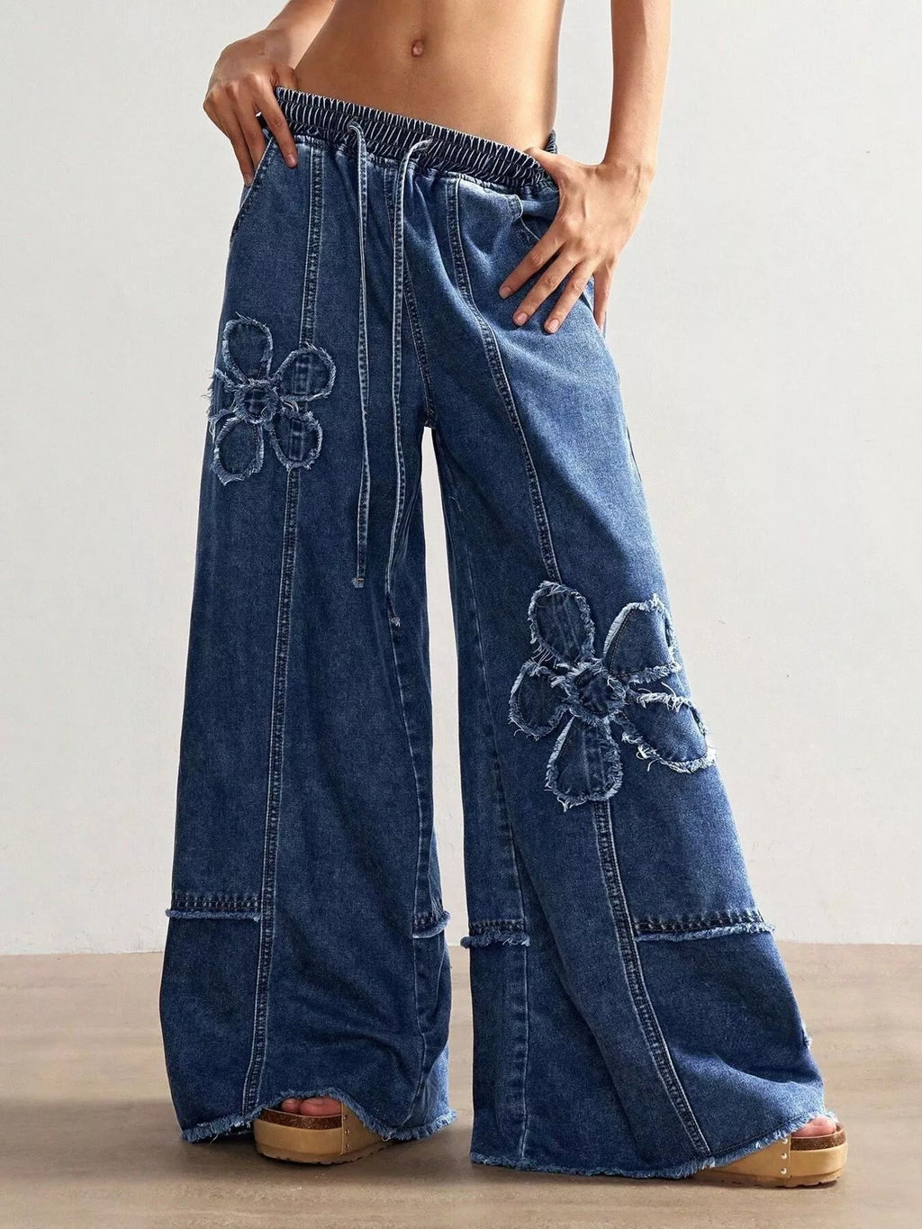 Wide leg jeans with floral appliques from Shopimist, showing detailed floral embroidery and relaxed fit design.