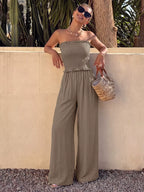 Smocked strapless wide-leg jumpsuit by Plush Fashion Hub with relaxed fit and stylish design, shown hanging on a hanger.