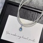 Double layered pearl necklace with teardrop pendant from Shopimist, featuring lustrous pearls and an elegant teardrop charm.